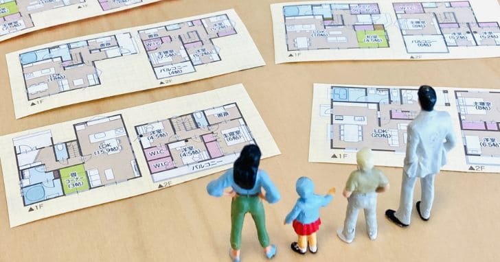 家の図面を見る家族の人形のイメージ