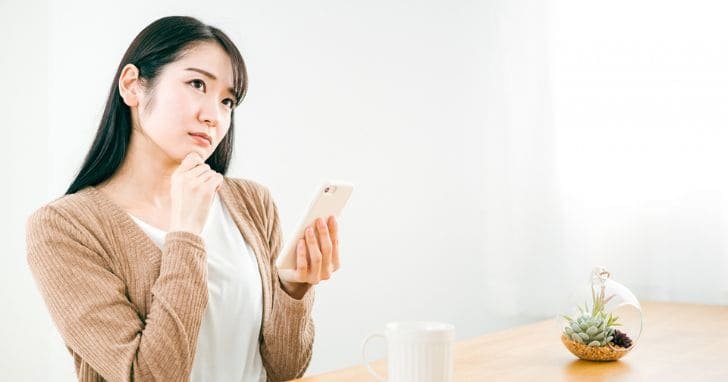スマートフォンを持ち悩む女性