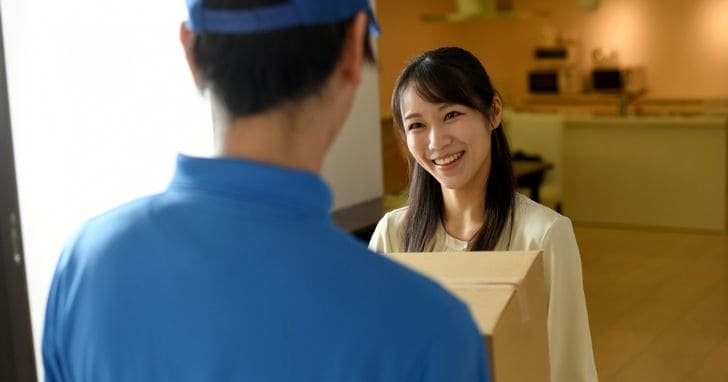 配送業者から荷物を受け取る女性