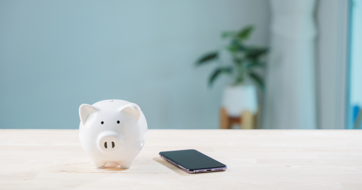 テーブルに置かれた豚の貯金箱とスマホのイメージ